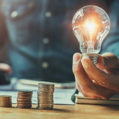 business man hand holding lightbulb with using calculator to cal